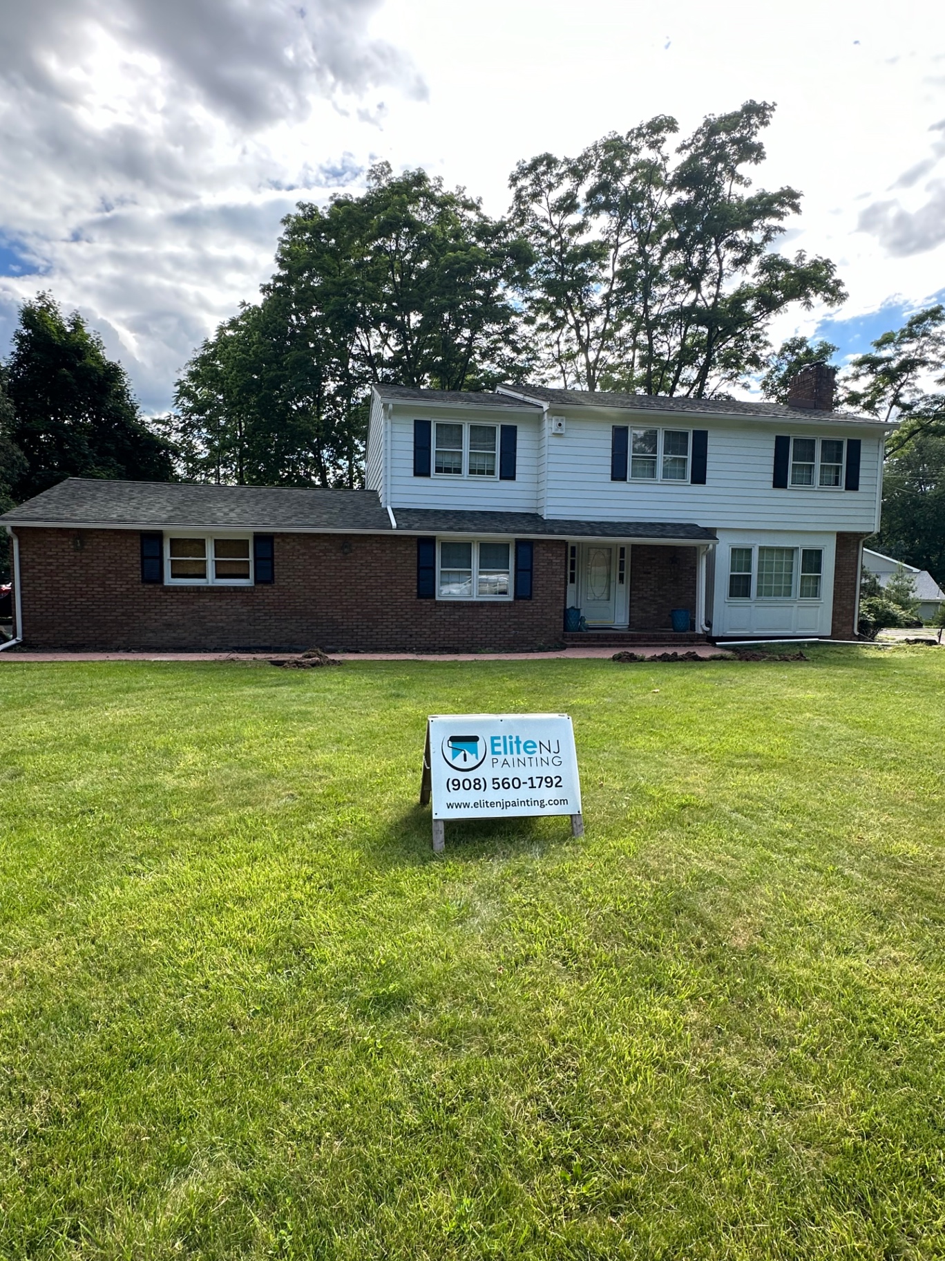 Two-story home exterior transformed with painted brick and updated siding — before