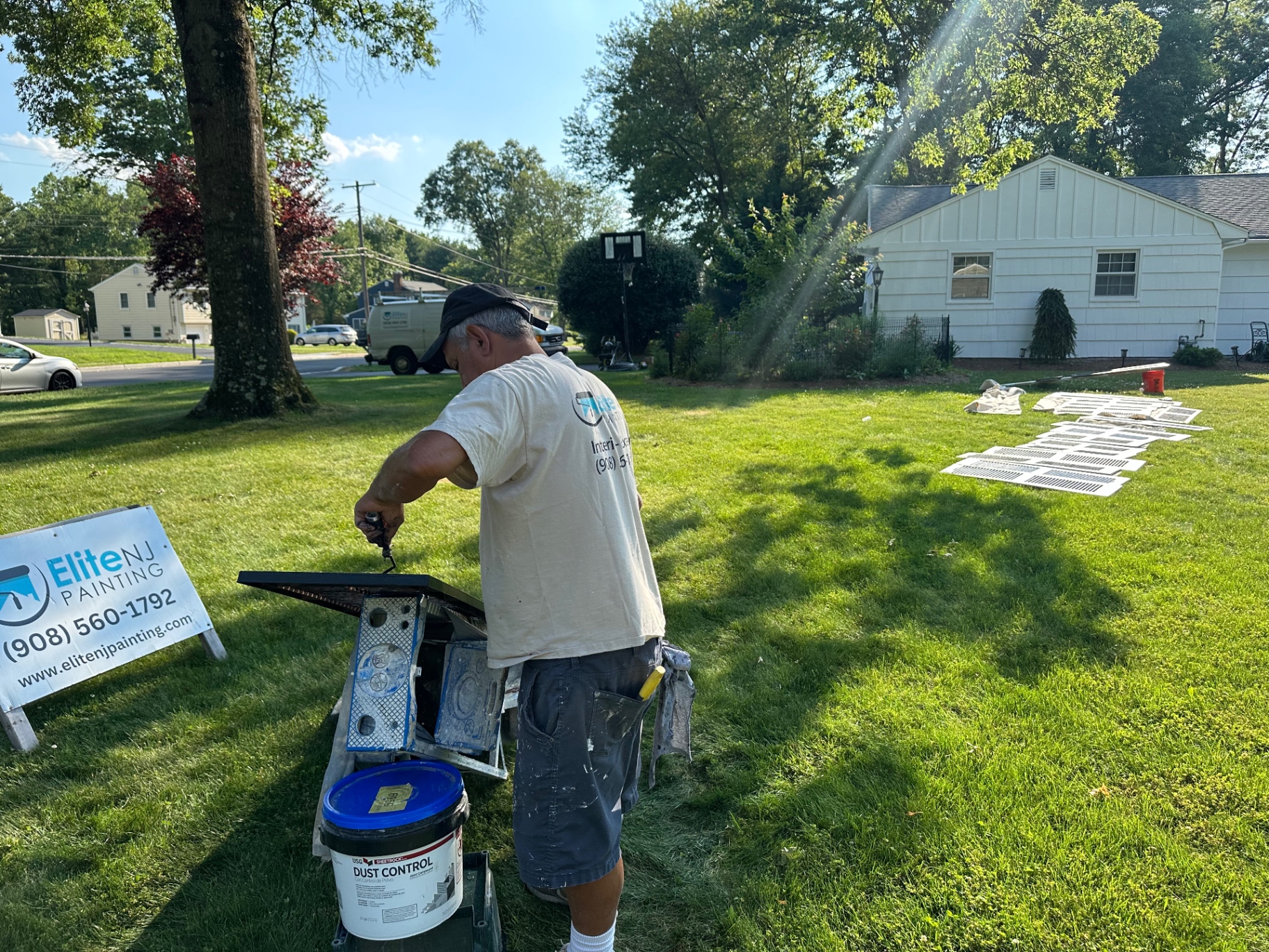 Elite NJ Painting crew member spray finishing exterior shutters on a residential job site