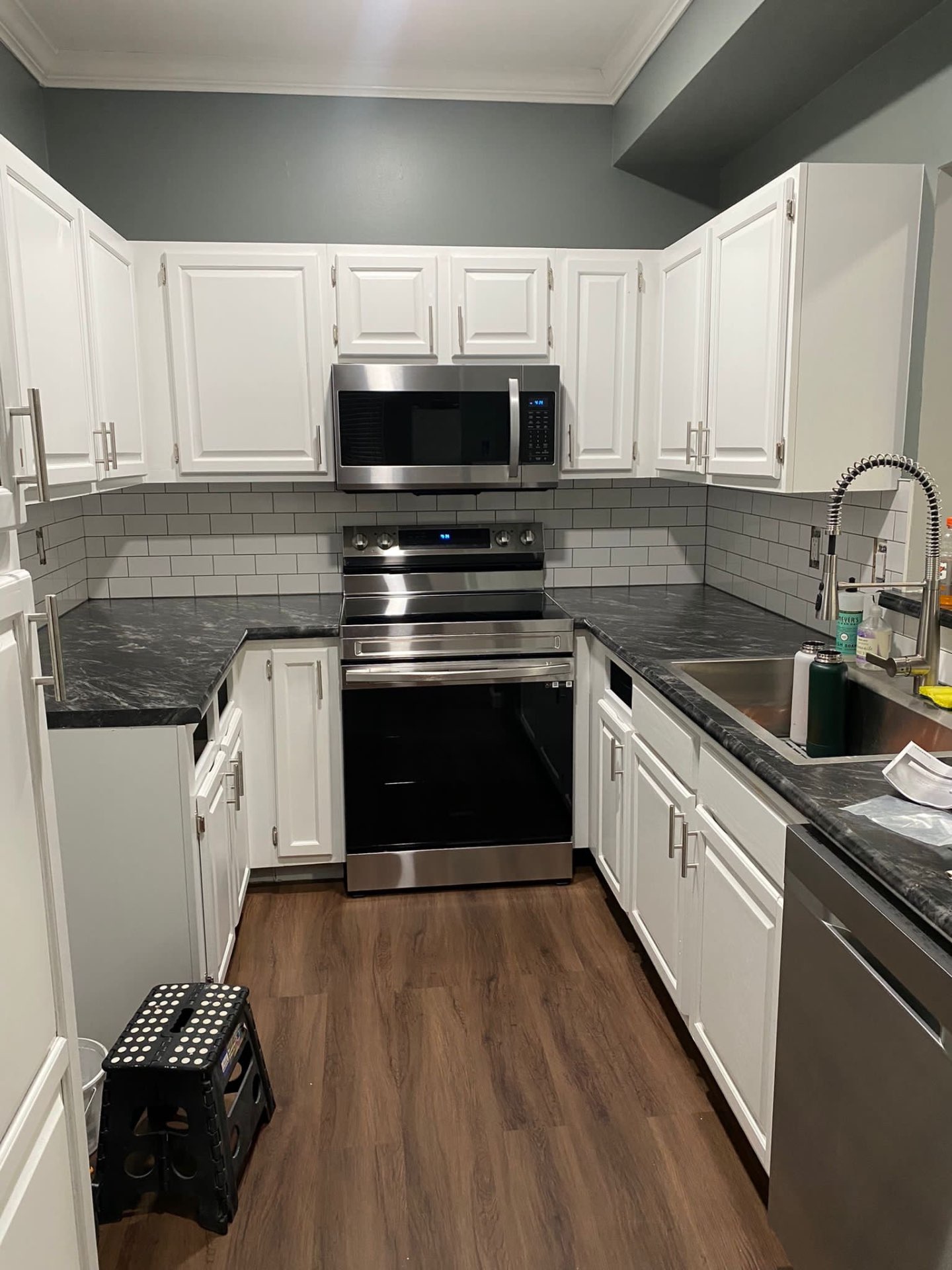 Compact kitchen with white refinished cabinets and deep gray-green painted walls