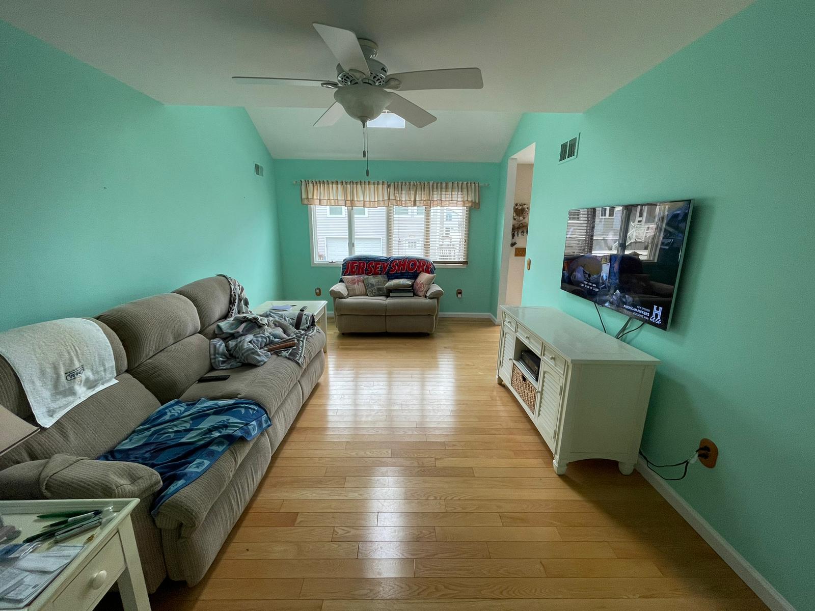 Living room repainted from bright teal to a soft warm gray — before