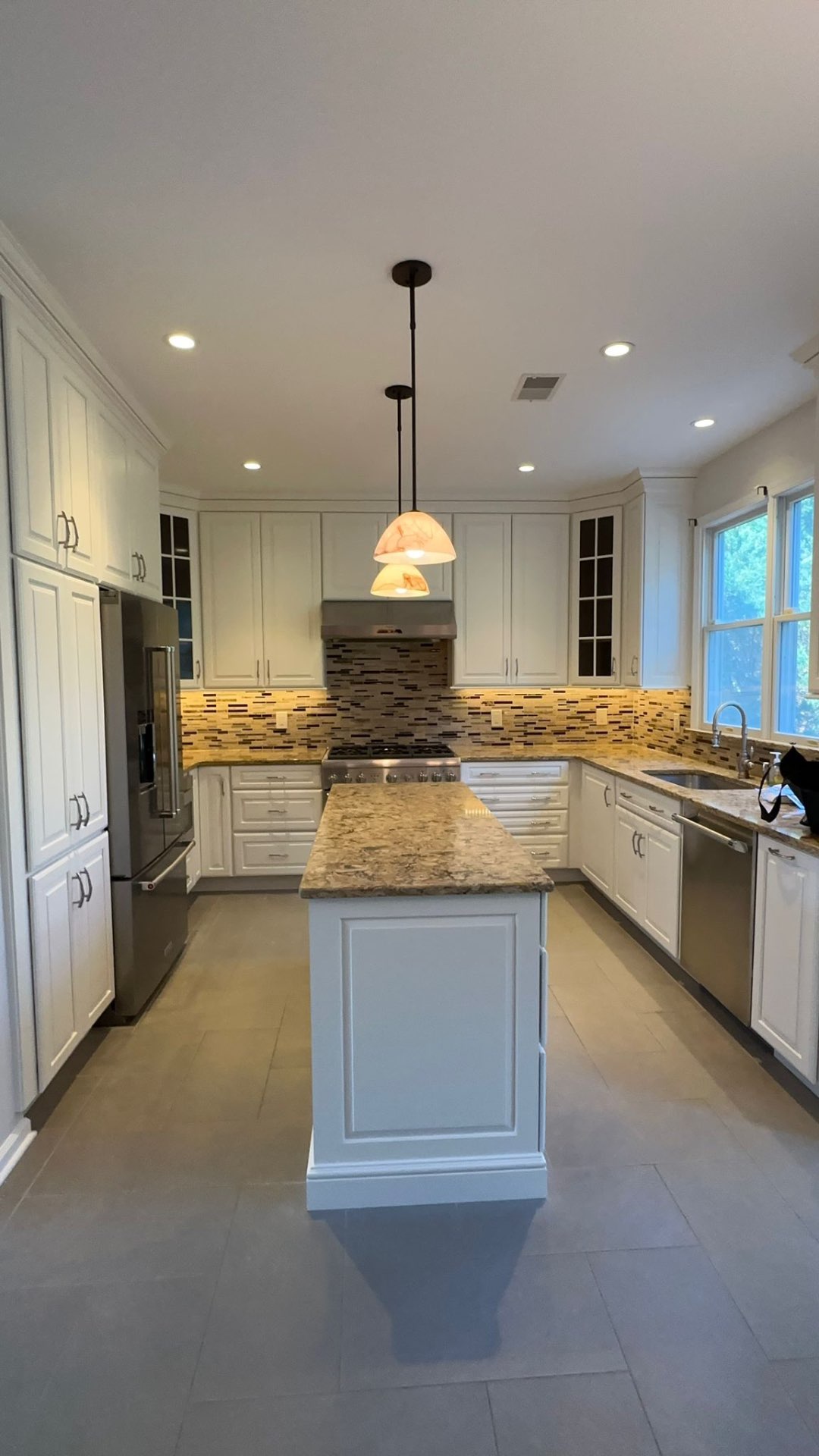 Kitchen with cabinets refinished in a crisp white satin finish and a granite island