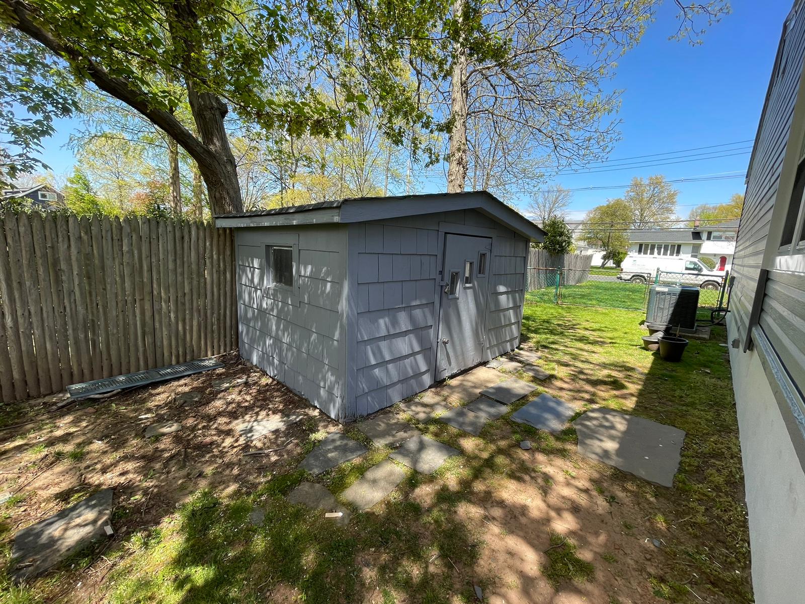 Weathered backyard shed with peeling paint restored with a clean gray exterior finish — after
