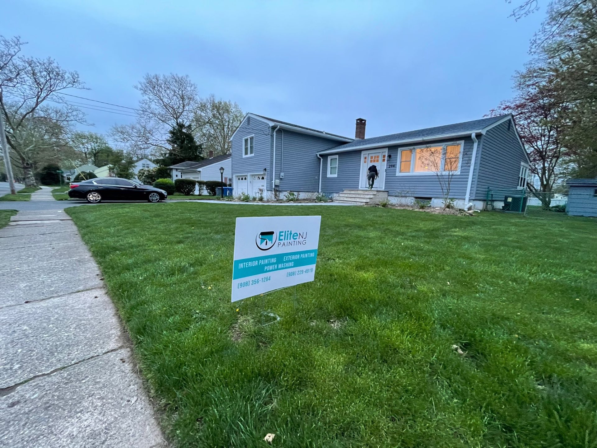 Elite NJ Painting yard sign in front of a gray split-level home