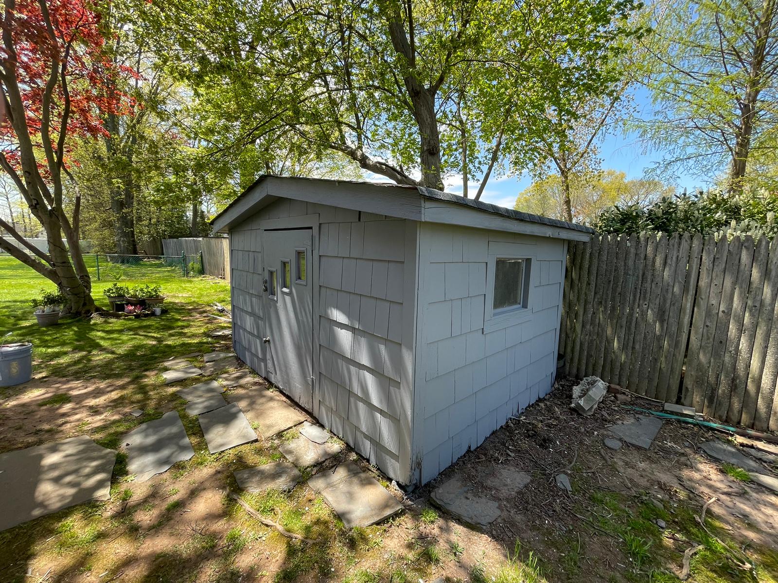 Backyard shed after painting, shown from the side with a smooth gray finish